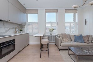 A modern kitchen with a marble countertop, a built-in oven, and a gas stove. - Modern 2BDR with Workspace in Clapham Junction (Greater London)