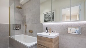 A modern bathroom with a freestanding bathtub, a glass-enclosed shower, and a vanity with a mirror. - Modern 2BDR with Workspace in Clapham Junction (Greater London)