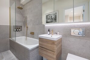 A modern bathroom with a freestanding bathtub, a glass-enclosed shower, and a vanity with a mirror. - Modern 2BDR with Workspace in Clapham Junction (Greater London)