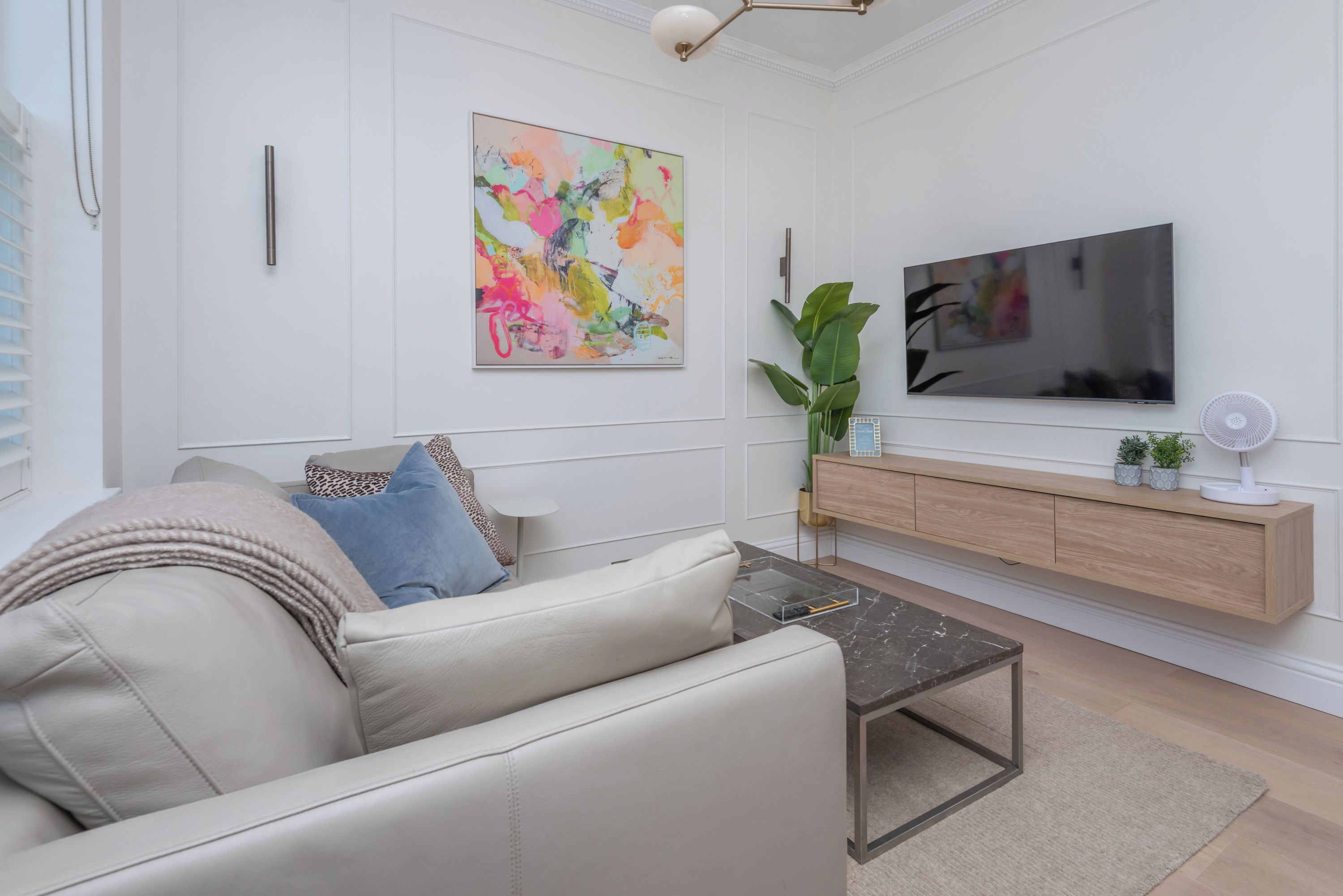 A modern living room with a sofa, a coffee table, a TV, and a plant.