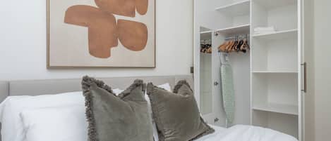 Un dormitorio con cama, armario y un cuadro abstracto grande en la pared.