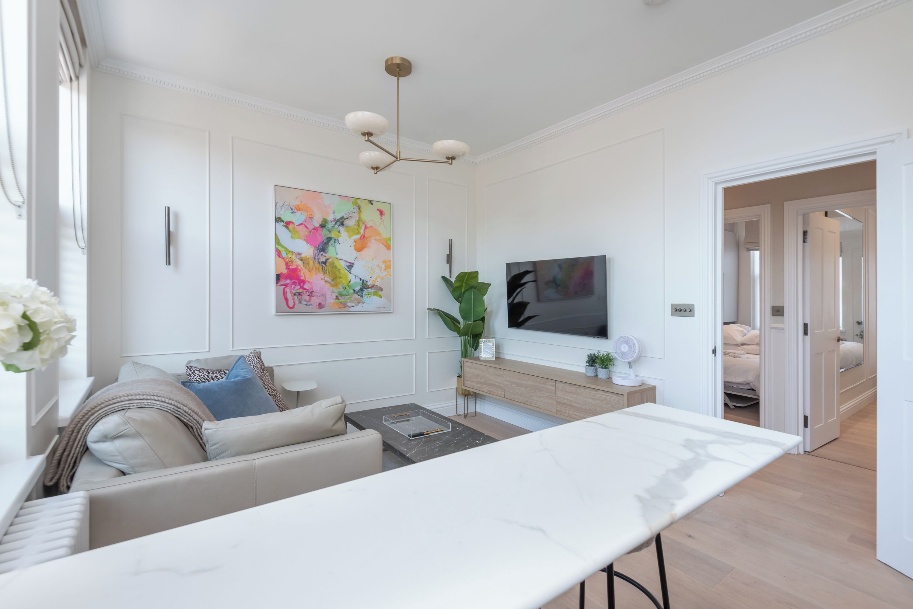 Ein modernes Wohnzimmer mit einer Couch, einem Couchtisch und einem an der Wand befestigten Fernseher.