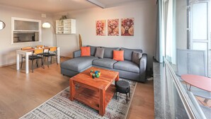 A modern living room with a grey sofa, a wooden coffee table, and a dining area with a white table and chairs. - Stunning apartment in Oostende with WiFi (Oostende)