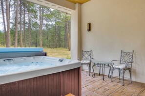 A hot tub with a view of a forest, a table, and two chairs. - Luxury Forest Retreat: Movie Room, Games, Hot Tub (Colorado Springs)