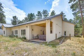 A modern single-story house with a covered patio, a hot tub, and a stone pathway leading to the entrance. - Luxury Forest Retreat: Movie Room, Games, Hot Tub (Colorado Springs)