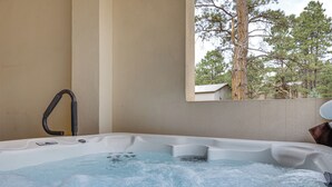 A hot tub with a view of trees through a window. - Luxury Forest Retreat: Movie Room, Games, Hot Tub (Colorado Springs)