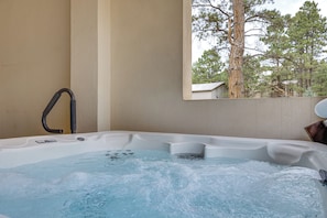A hot tub with a view of trees through a window. - Luxury Forest Retreat: Movie Room, Games, Hot Tub (Colorado Springs)