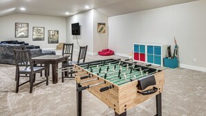 A room with a foosball table, chairs, a table, and a sofa. There are posters on the wall and a speaker mounted on the wall. - Luxury Forest Retreat: Movie Room, Games, Hot Tub (Colorado Springs)