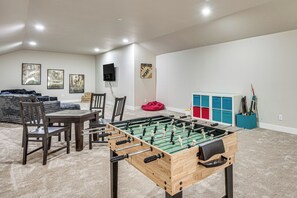 A room with a foosball table, chairs, a table, and a sofa. There are posters on the wall and a speaker mounted on the wall. - Luxury Forest Retreat: Movie Room, Games, Hot Tub (Colorado Springs)