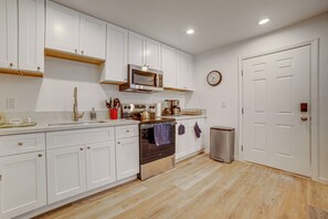 A kitchen with white cabinets, a stainless steel oven, a microwave, and a clock on the wall. - 4 Mi to Riverside Medical Center! Extended Getaway (Riverside)