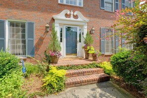 A brick building with a white door, two potted plants, and a small garden area. - Group Getaway w/ Private Yard in Marietta (Marietta)