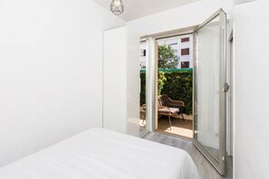 A bedroom with a bed, a sliding glass door leading to an outdoor seating area with a chair and a table. - Maupassant Terrace | 2 min from the beach (Antibes)