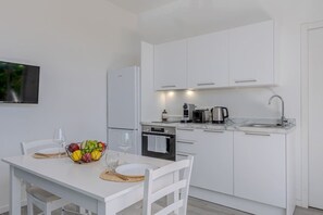 Eine moderne Küche mit weißen Schränken, einem Backofen, einer Kaffeemaschine und einem Spülbecken.