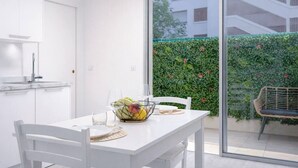 Een moderne keuken met witte kasten en een eethoek met een tafel gedekt voor twee personen.