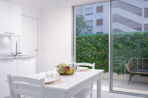 A modern kitchen with white cabinets and a dining area with a table set for two. - Maupassant Terrace | 2 min from the beach (Antibes)