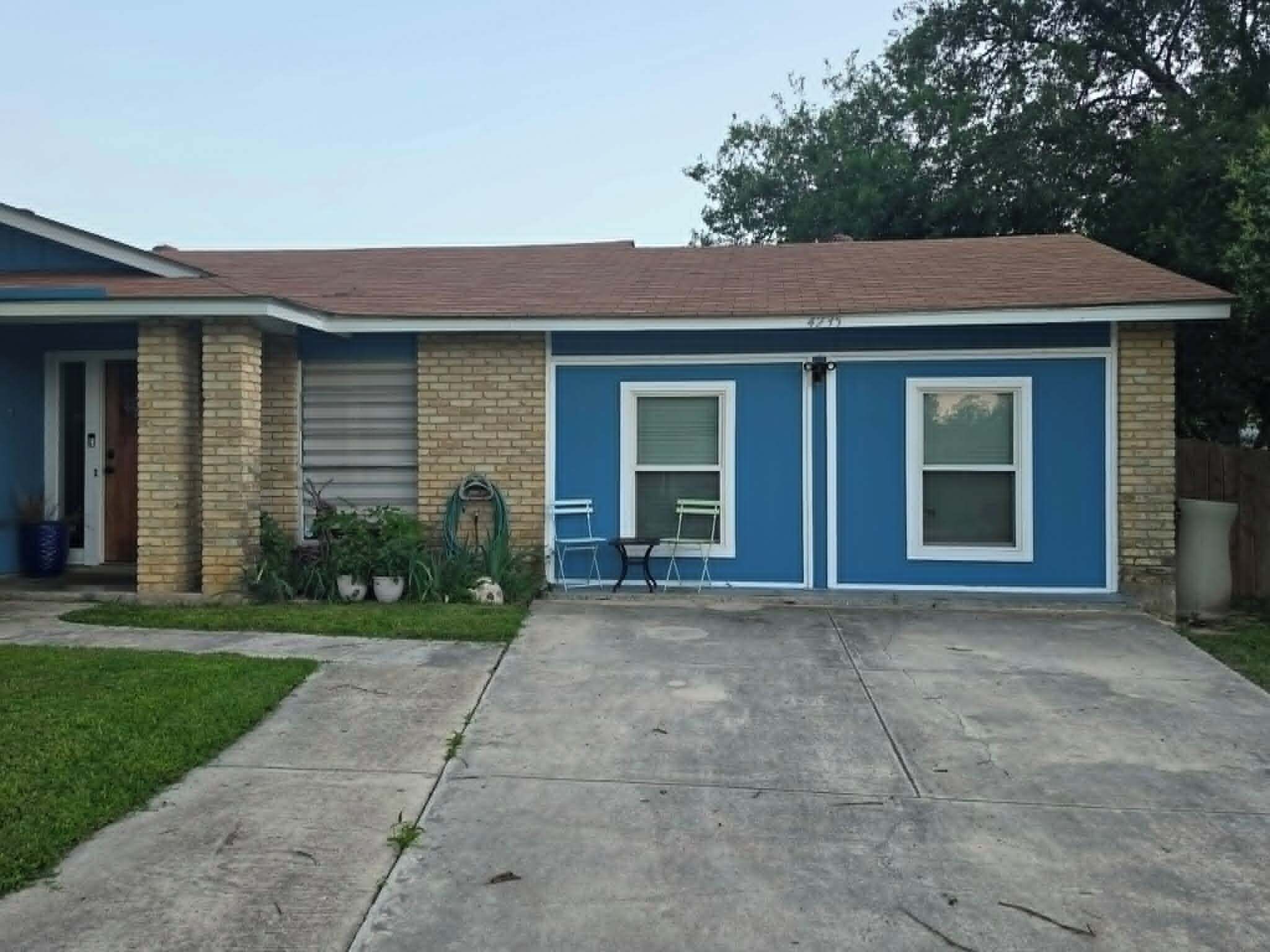 A residential house with a garage, a front door, and a small patio area with two chairs and a table.