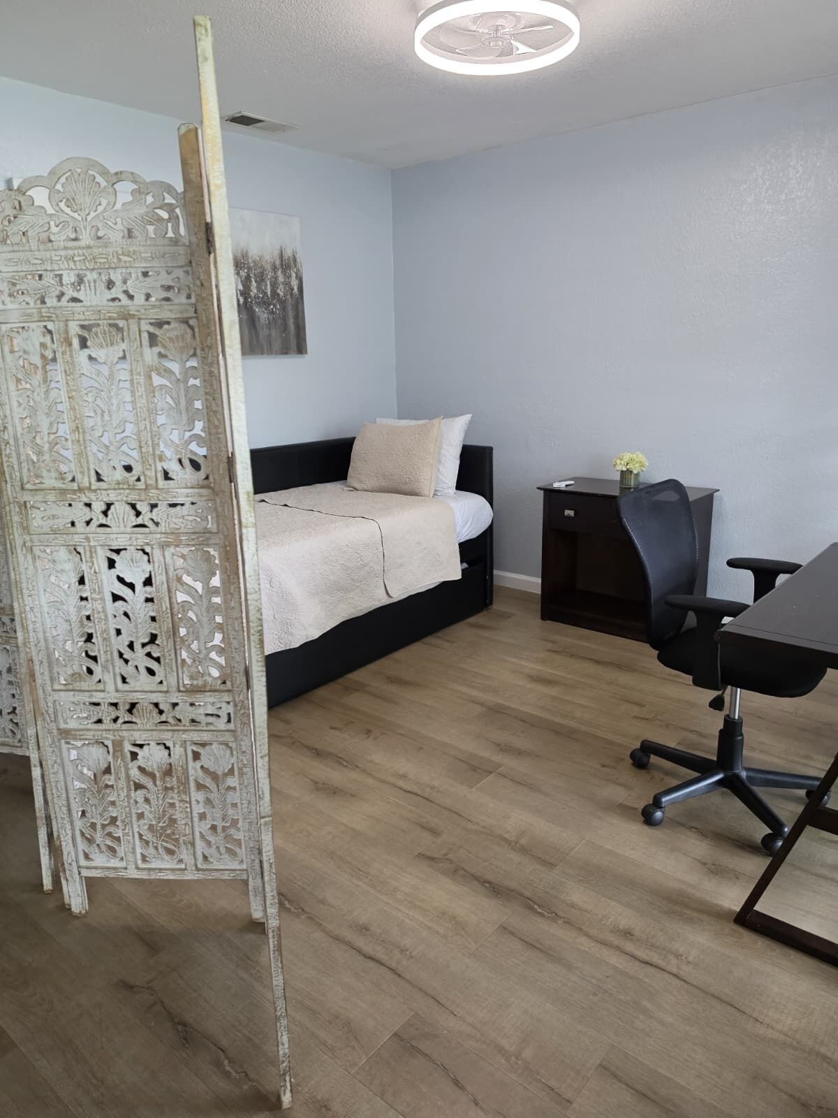 A bedroom with a bed, a desk, and a chair.