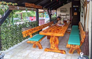 Ein Holzbänkchen und Tisch in einer überdachten Außenbereich mit Steinboden.