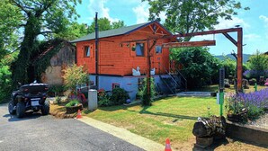 A rustic cabin with a red exterior, a wooden porch, and a small garden with flowers and a bird bath. - Beautiful home in Ludbreg with sauna (Ludbreg)