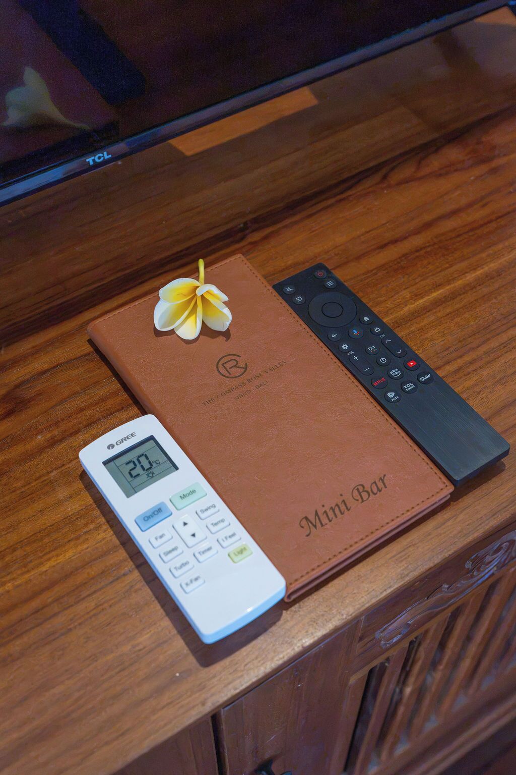 Um controle remoto, um termostato digital e um livro de couro sobre uma superfície de madeira.