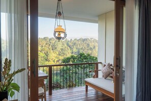 A balcony with a wooden floor, a hanging light fixture, and a view of a forested landscape.