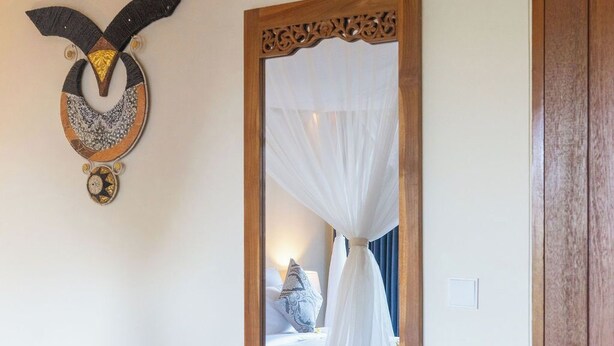 Una habitación con cama, un espejo y una puerta de madera.