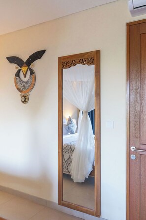 A room with a bed, a mirror, and a wooden door. - The Compass Rose Valley (Taro)