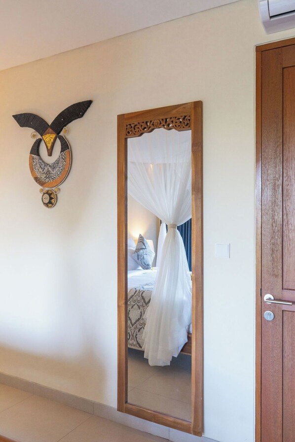 A room with a bed, a mirror, and a wooden door.