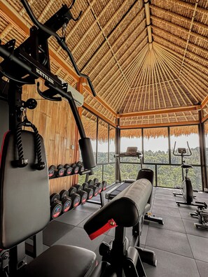 A gym with exercise equipment, a bench, and a rack of dumbbells.