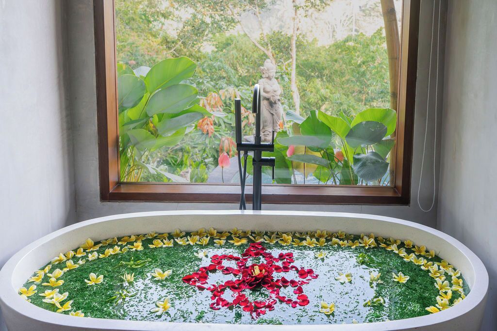 Una bañera con un arreglo floral y una estatua al fondo.