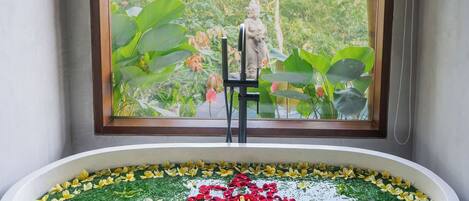 Una bañera con un arreglo floral y una estatua al fondo.