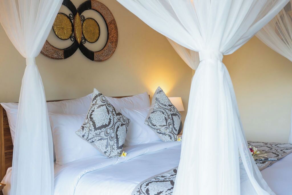 A bed with a canopy, patterned pillows, and a wall decoration.