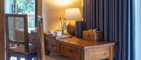 A wooden desk with a lamp, a chair, and a window with curtains.