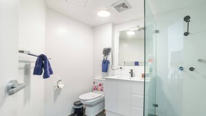 A modern bathroom with a toilet, sink, and shower area. - Room-classic Family Room - Sleeps 4 (Sydney)