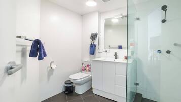 A modern bathroom with a toilet, sink, and shower area.