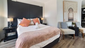 A hotel room with a large bed, two bedside tables, a chair, and a decorative wall piece. - Room-classic Family Room - Sleeps 4 (Sydney)