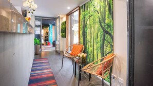 A hallway with a colorful striped rug, wicker chairs with orange cushions, and a forest-themed wall mural. - Room-classic Family Room - Sleeps 4 (Sydney)