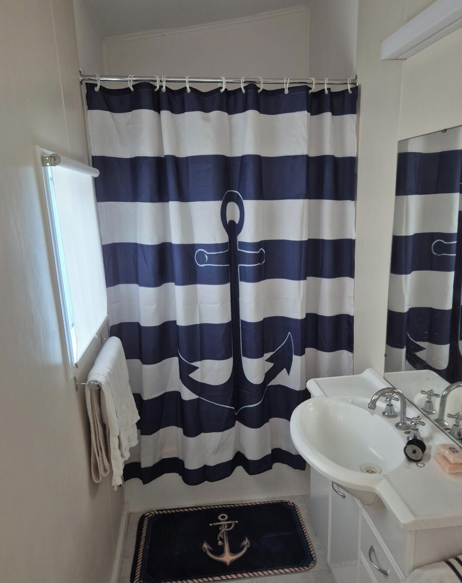 A bathroom with a striped shower curtain, a sink, a mirror, and a towel rack.