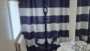 A bathroom with a striped shower curtain, a sink, a mirror, and a towel rack.