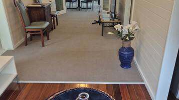 A hallway with a wooden floor, a dining area with chairs and a table, and a decorative rug with an anchor design.