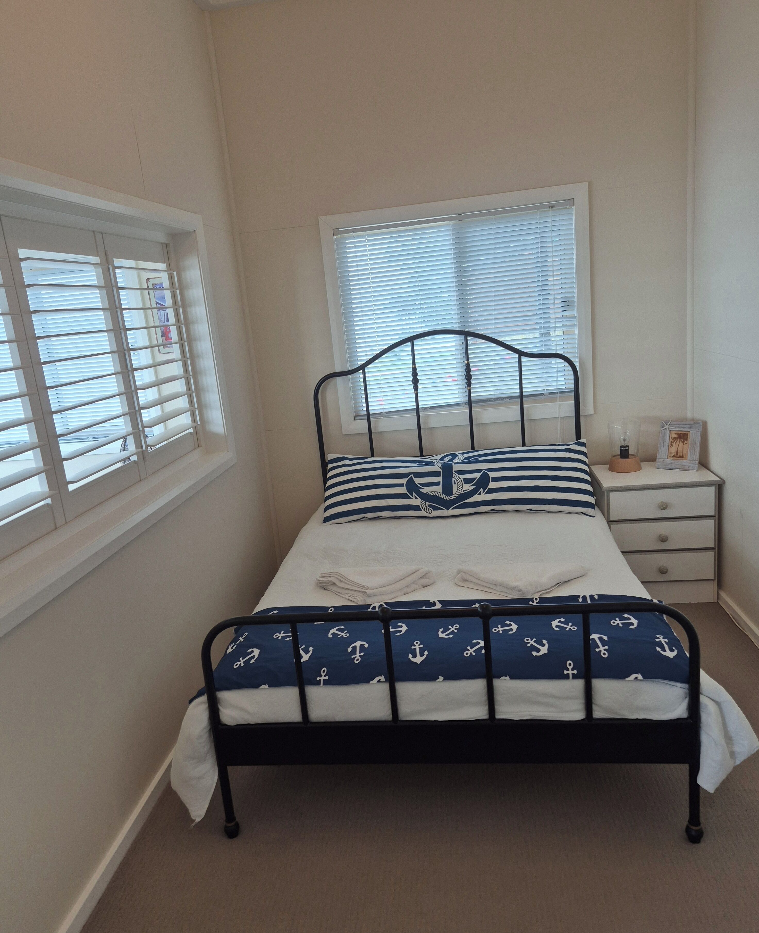 Une chambre à coucher avec un lit, une table de chevet et une fenêtre avec des stores.