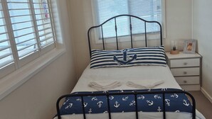 Ein Schlafzimmer mit einem Bett, einem Nachttisch und einem Fenster mit Jalousien.