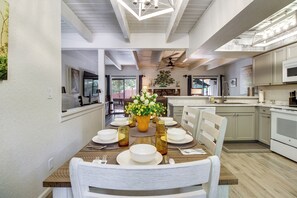 A modern kitchen with white cabinets, a dining area with a wooden table set for four, and a ceiling fan. - Great for Families! Pinetop Sanctuary w/ Patio (Pinetop)