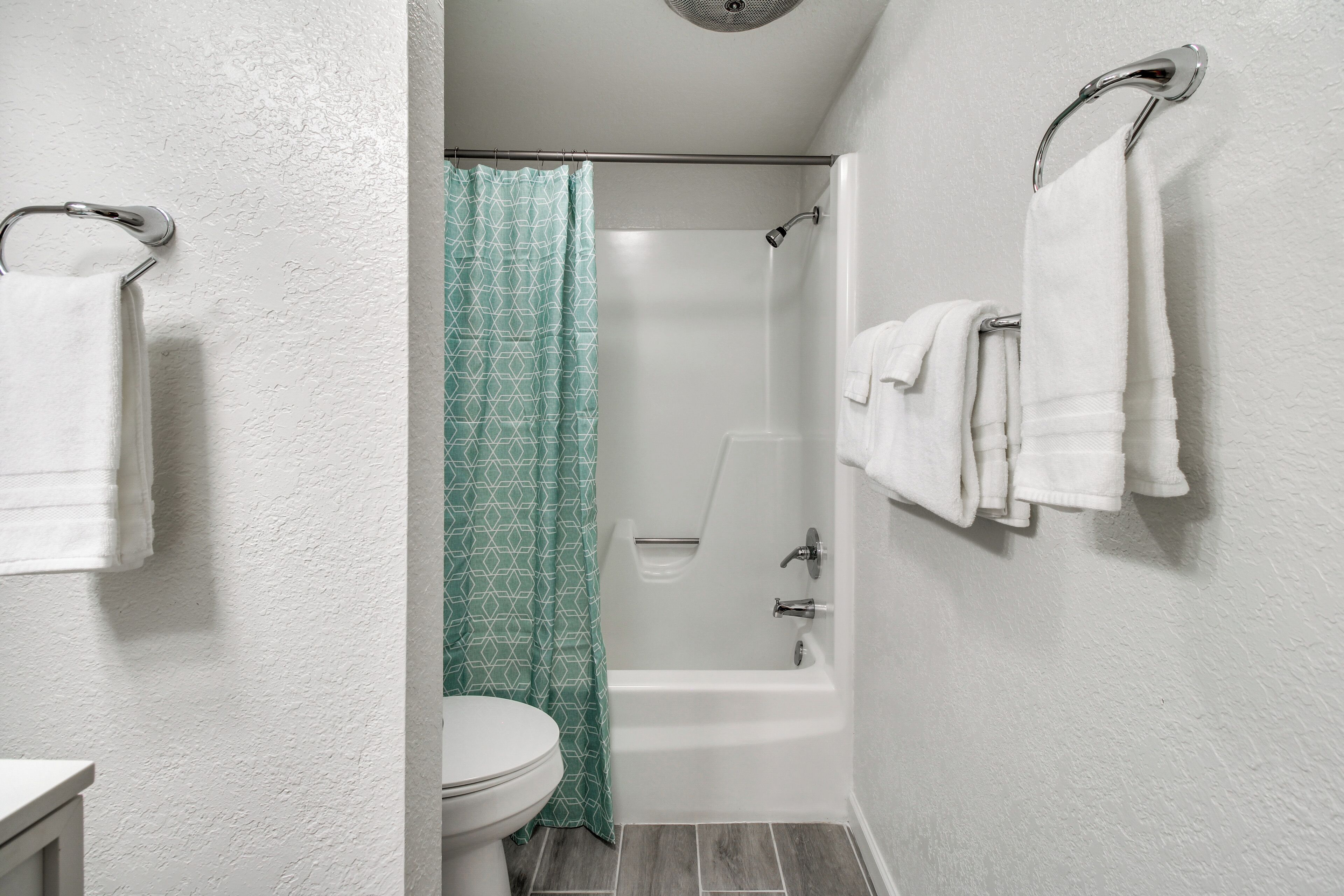 Ein Badezimmer mit Toilette, Badewanne und Dusche. Handtücher hängen an der Wand.