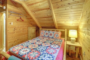 A wooden room with a bed, a hanging coat rack, and a lamp. - Rustic Cabin w/ Phoenix Mtn Views & Trail Access! (Lansing)