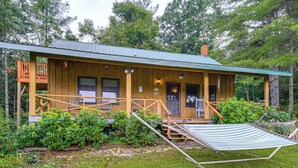 Eine Holzhütte mit Veranda, Hängematte und kleiner Terrasse.