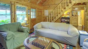 Ein gemütliches Holzhaus-Interieur mit einer Couch, einem Schachtisch und einer Treppe.