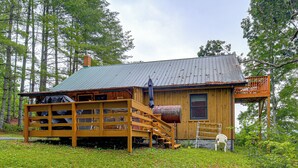 Eine Holzhütte mit einer Holzterrasse, einem Metalldach und einer kleinen Veranda.