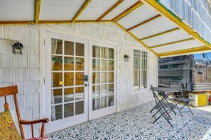 A covered patio with a tiled floor, a wooden chair, a table, and a grill area. - Extended Group Getaway 2 Mi to Dtwn & Ybor City! (Tampa)