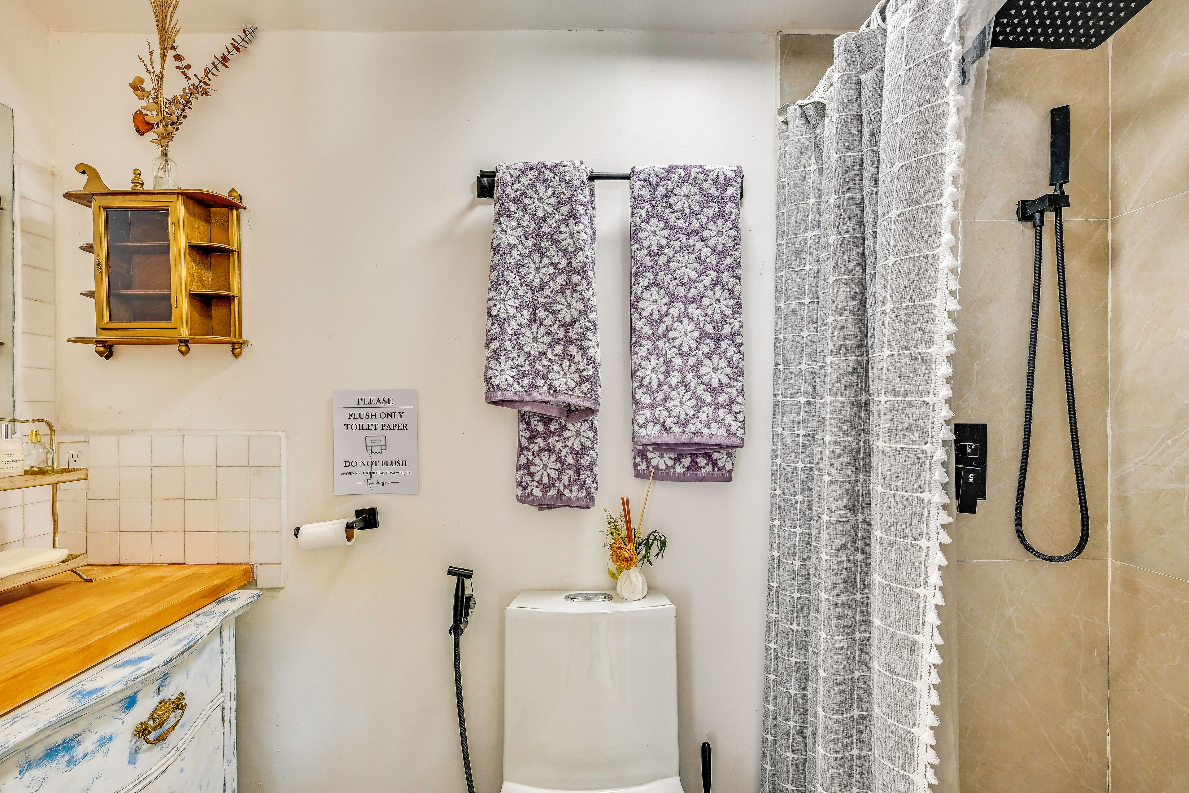 A bathroom with a toilet, a shower, and a towel rack with patterned towels.